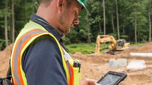 Construction worker looking on IPad on construction site.