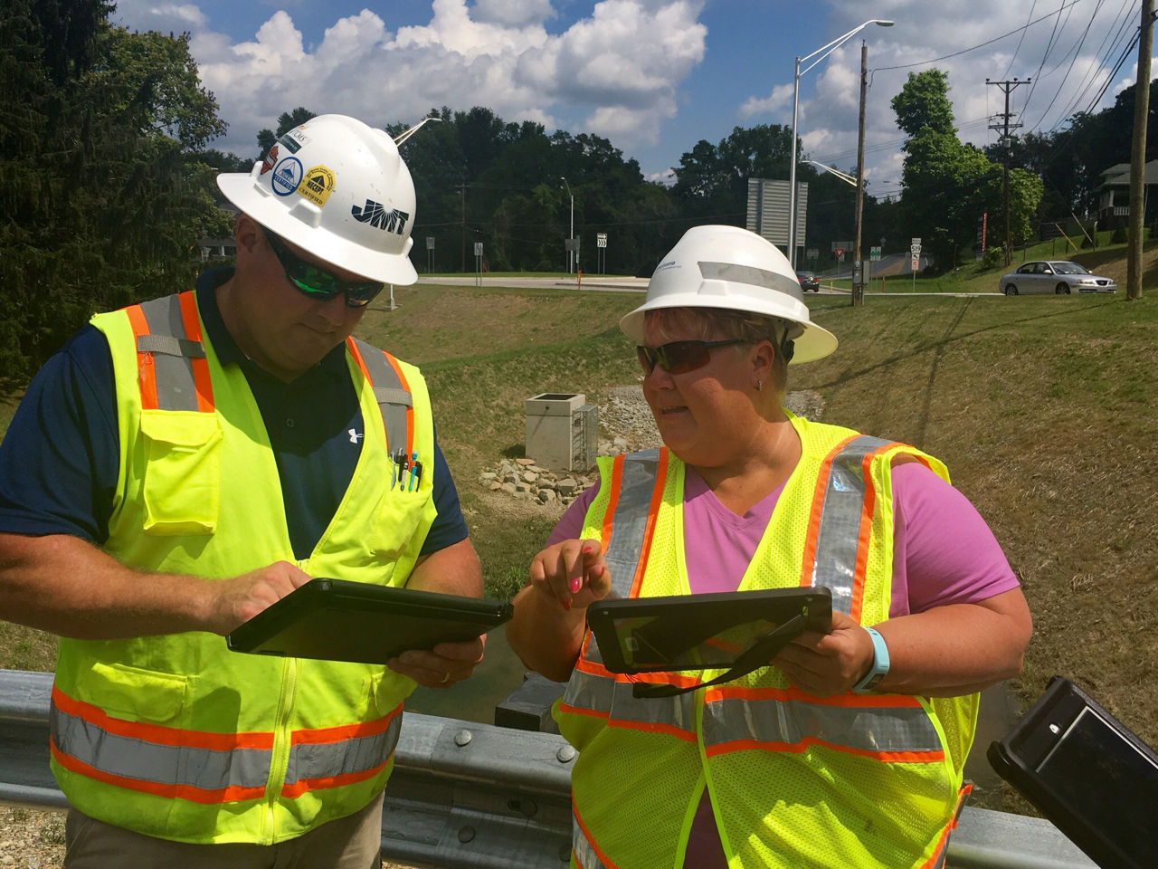 Two individuals at a construction site looking at an iPad