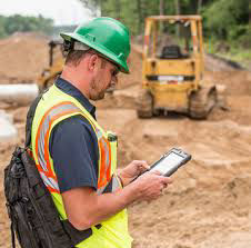 An individual on a construction site looking at an iPad.