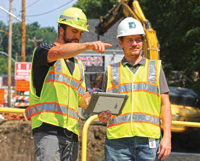 Two people on a construction site looking at an iPad.