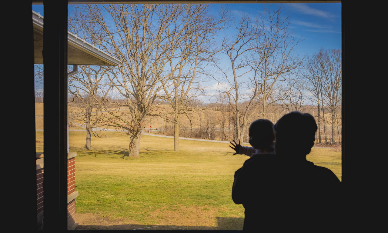 A family experieincing effects from a disaster looks out the window.