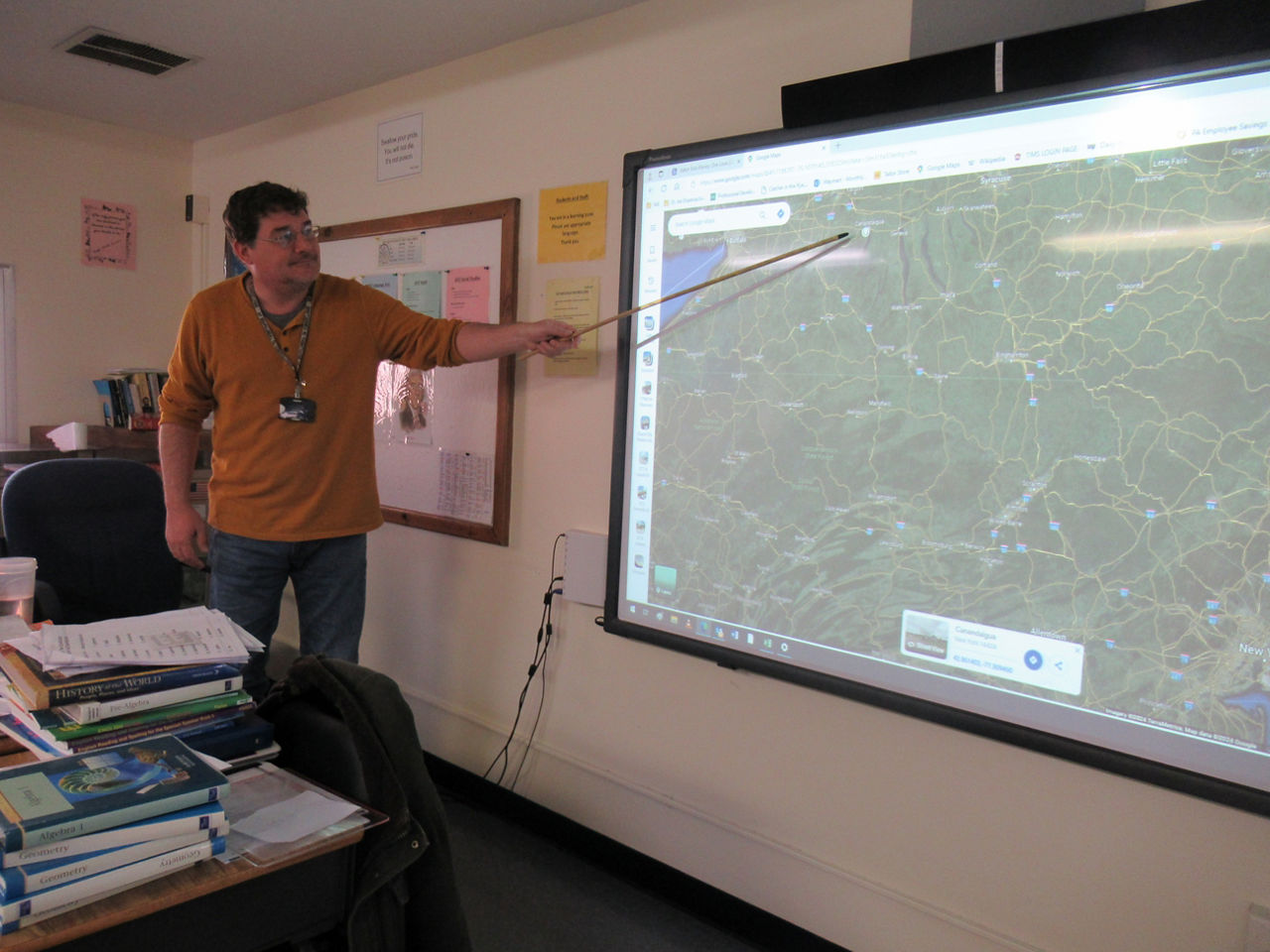 A teacher points to a map on a screen
