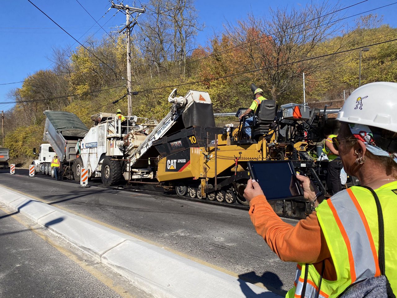 construction worker taking picture of paving equipment