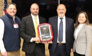 Labor & Industry Secretary stands with Etzel Engineer and Build leadership holding a 2025 GASE plaque