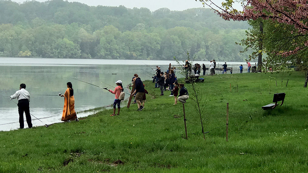 Medium shot of a group of families learning to fish at a lake 