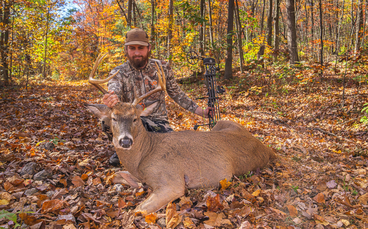 Hunter in fall holding up a Deer 