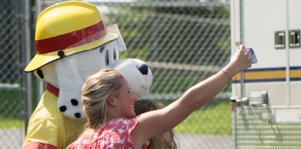 Staff members and kids line up to take pictures with Sparky the Fire Dog.