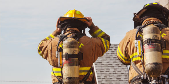 image of two firefighters, with one holding on to their helmet