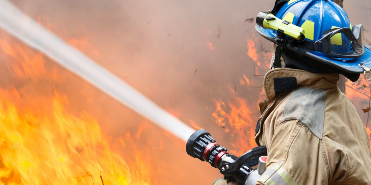 A firefighter hits a blaze with a hose.