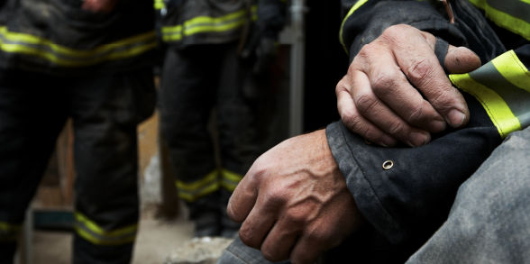 A firefighter carries a child who is holding a stuffed bunny.