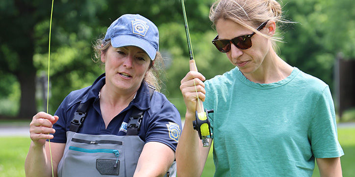 PFBC Educator teaches a woman how to cast a fly fishing rod