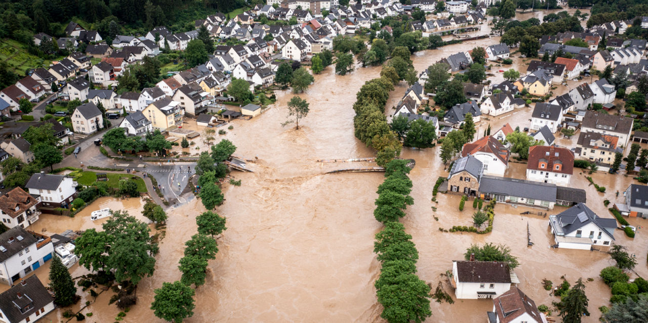 A flooded community with water past first levels of homes and up to the top of trees.