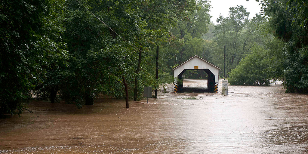 Floods overtake a covered bridge.