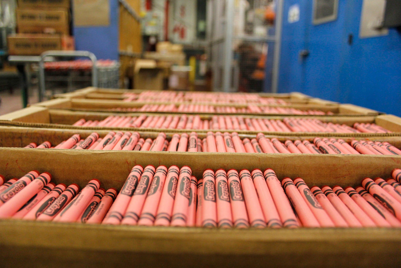 Red Crayola crayons sit in large boxes in a Crayola factory