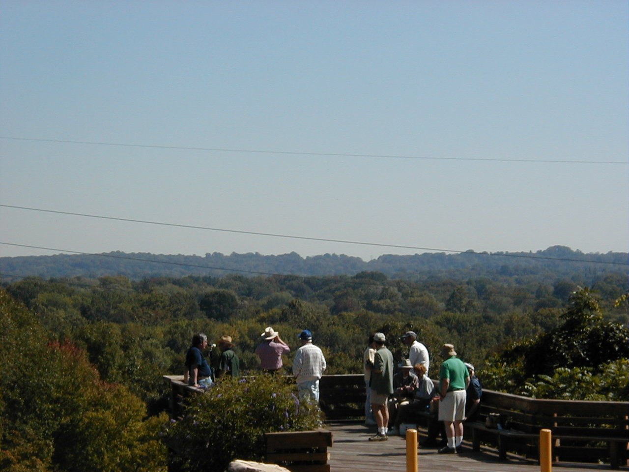 A group of people standing on an overlook platform viewing the mountains 