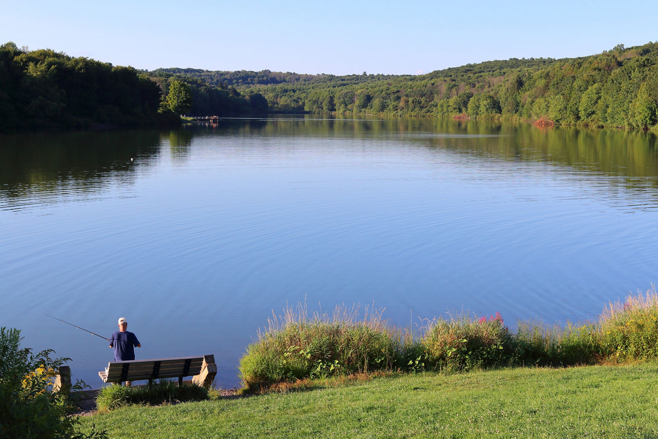 A fisherman near a blue lake on a sunny day