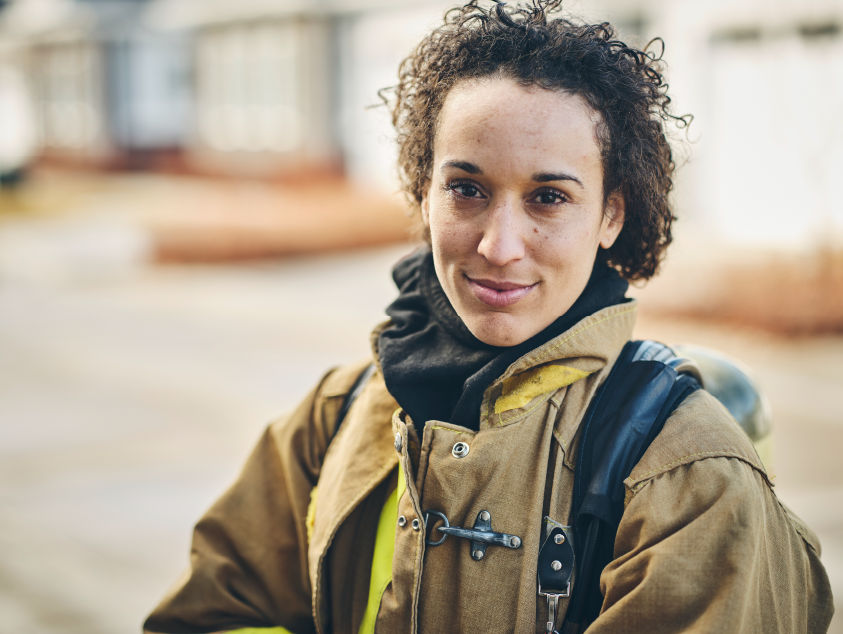 A woman in firefighter gear stares at the camera.