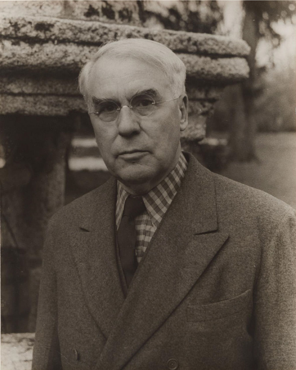 Elderly man in suit outdoors near stone structure