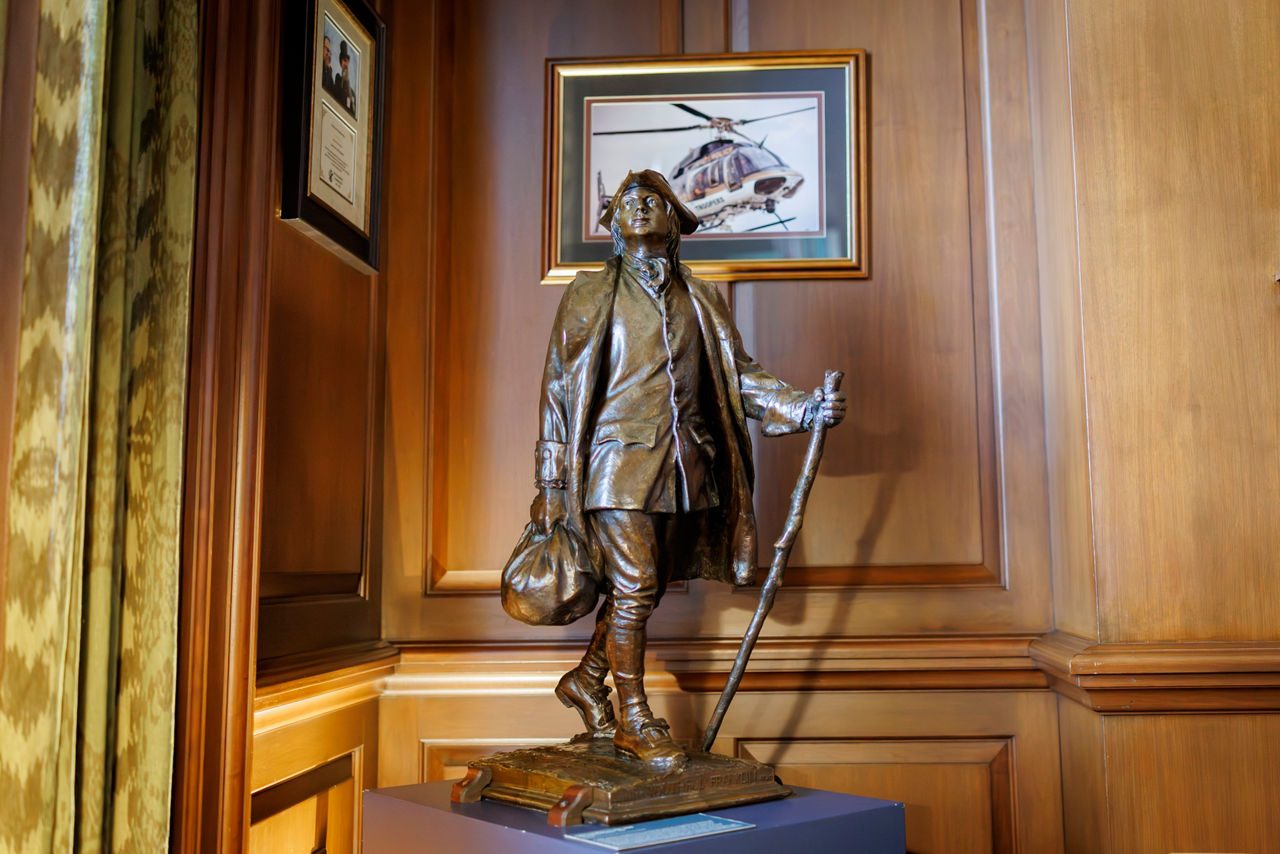 Bronze statue of historical traveler in wood-paneled room