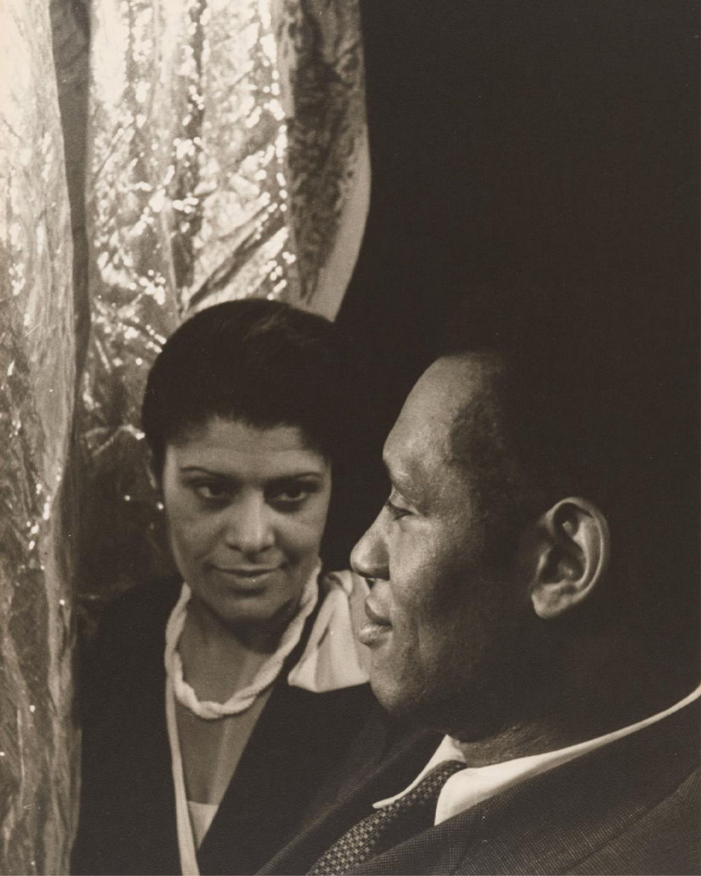 Monochrome portrait of two people near draped fabric