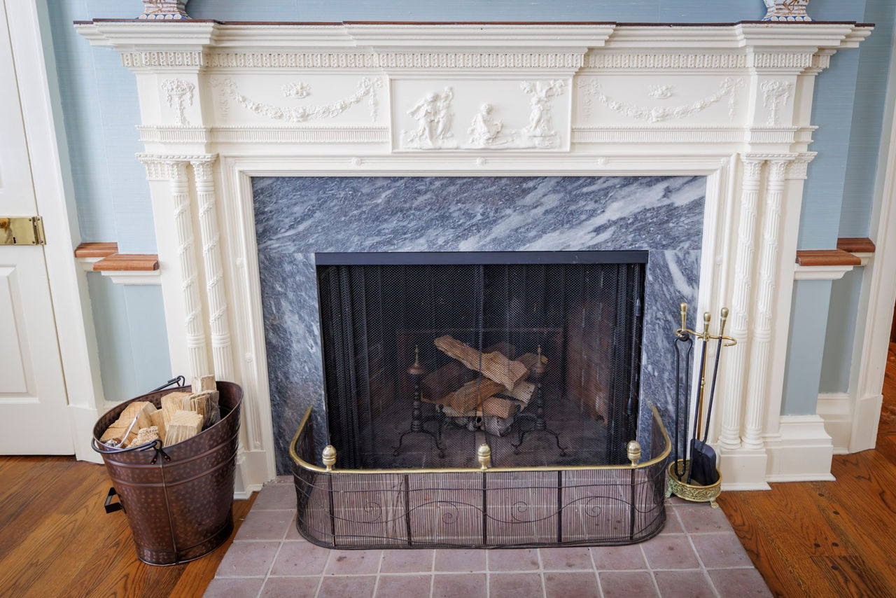 Classic marble fireplace with firewood and ornate mantel