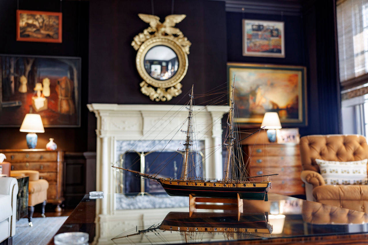 Model ship displayed in elegant parlor with a white mantelpiece.