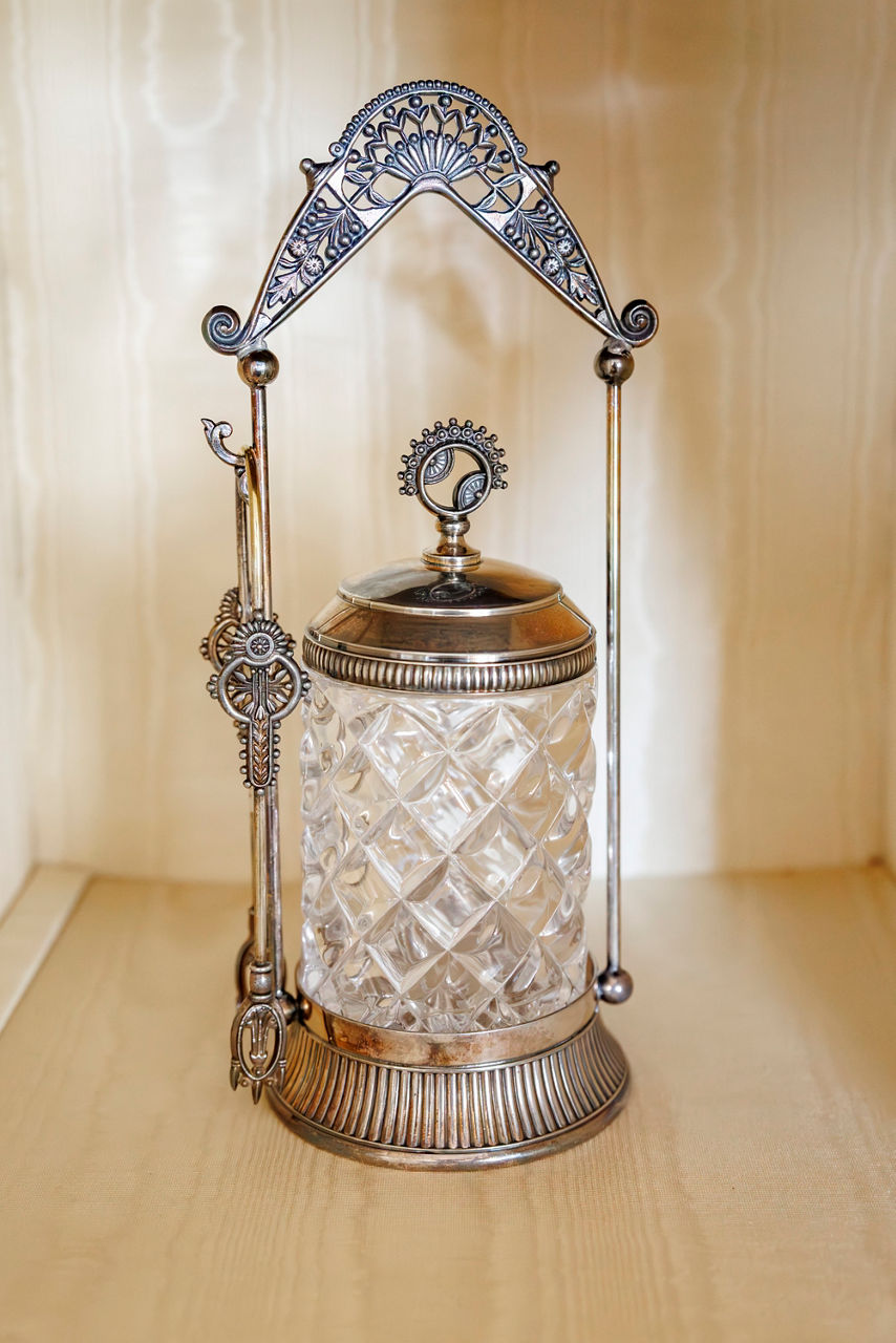 Ornate cut glass pickle jar with intricate floral designs on the silver handle and lid.