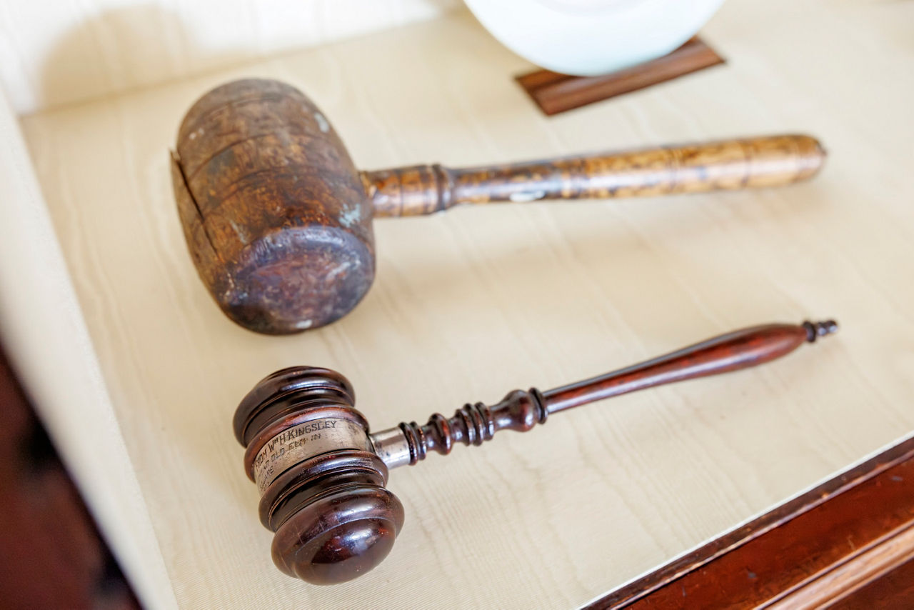 Two wooden gavels. The larger gavel appears worn and rustic, while the smaller one is polished.