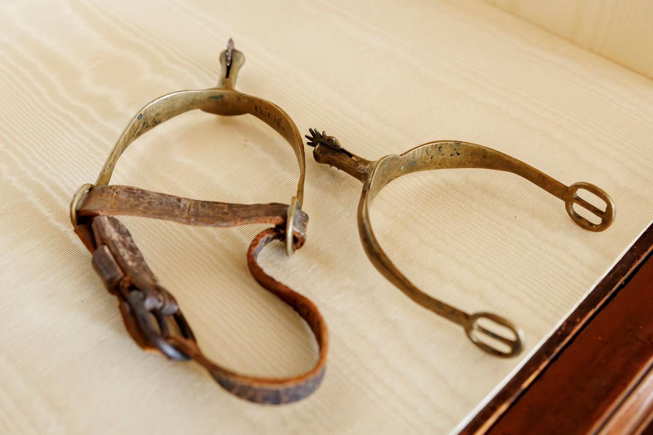 A pair of antique brass spurs with leather straps.