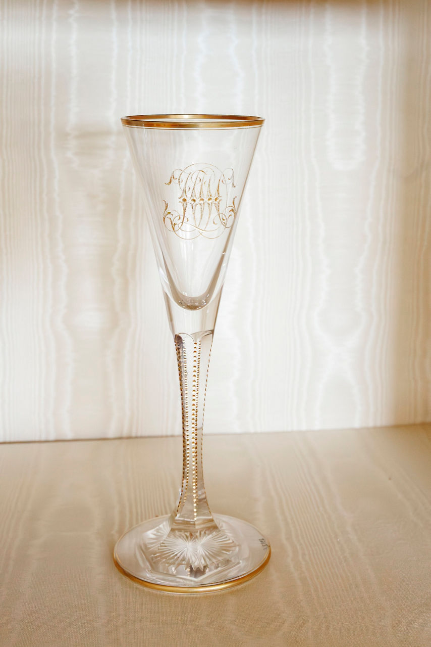 Elegant clear wine glass with gold rim and intricate monogram design.