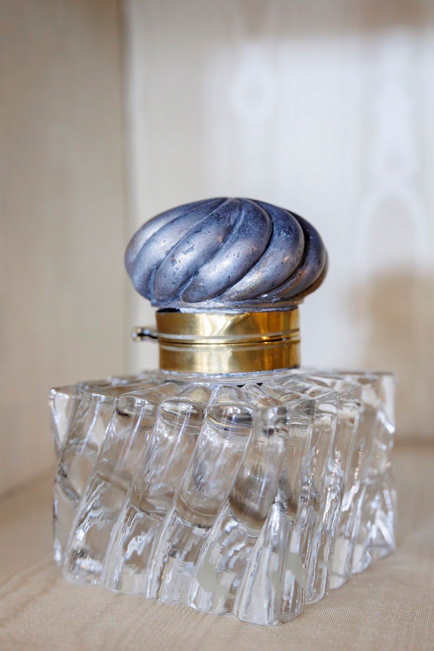 Vintage glass perfume bottle with a textured, twisted design. It features a swirling zinc cap with a brass band.