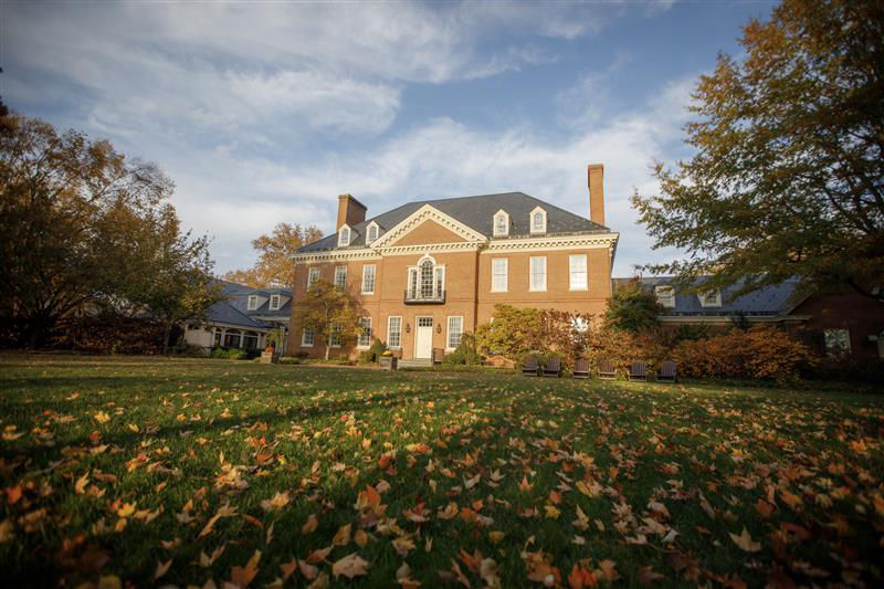 The Residence being lit up at sunset with fall leaves on the ground