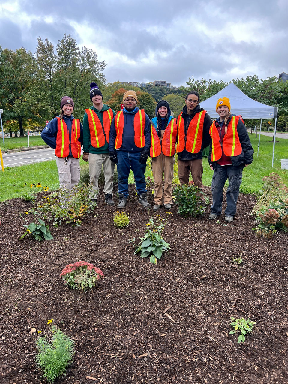 A group of PA Outdoor Corps staff pose for a photo while wearing visibility vests.