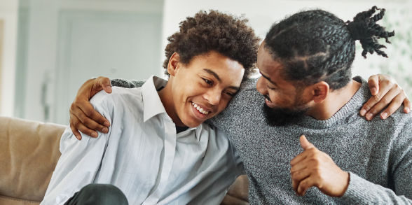 A father and son cuddle while chatting.