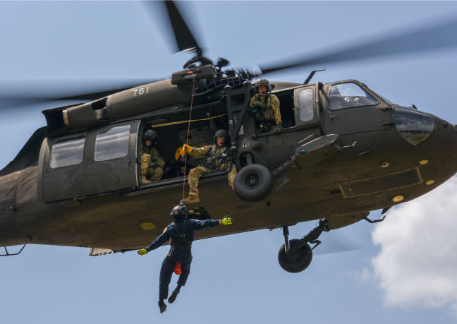 A member of the Pennsylvania Helicopter Aquatic Rescue Team dangles from a helicopter.