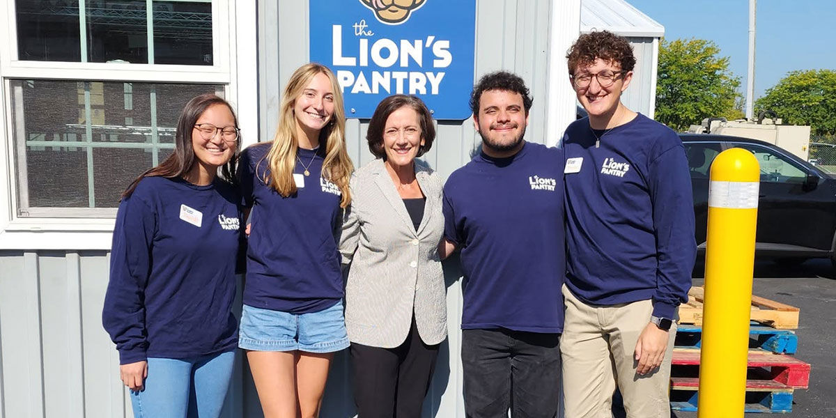 PA DHS Secretary Val Arkoosh with students posing in front of the Lion's Pantry food bank at Penn State's main campus.