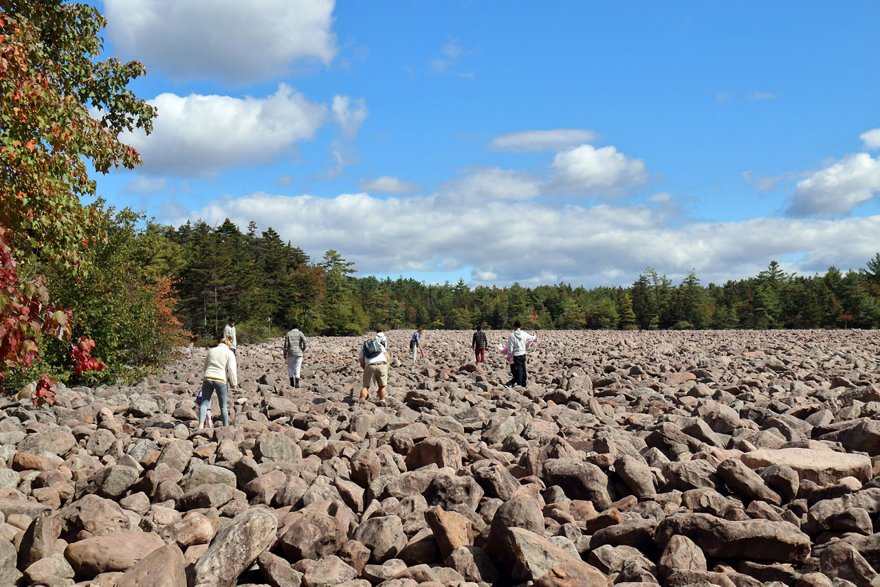 A group of people walking across boulders in Boulder Field