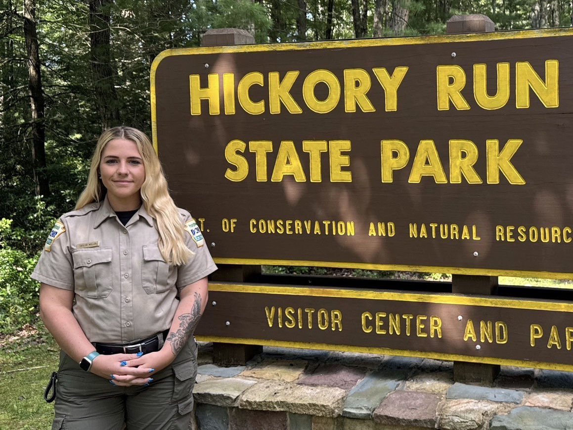 Assistant Park Manager Taylor Miller stands in front of the Hickory Run State Park sign.