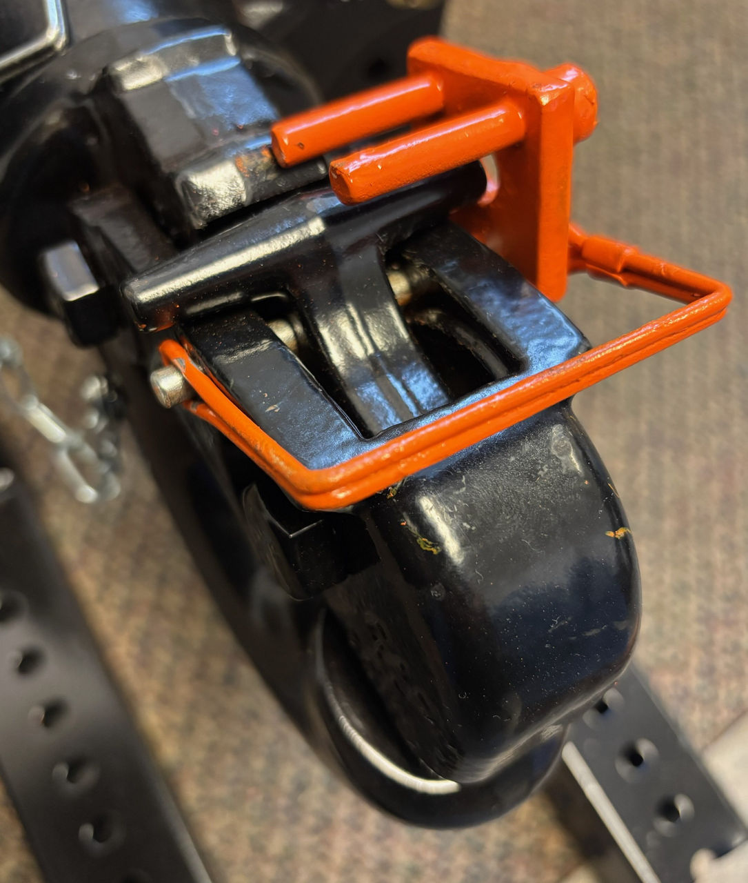 An orange hitch pin with two additional guide pins sits on top of a table.