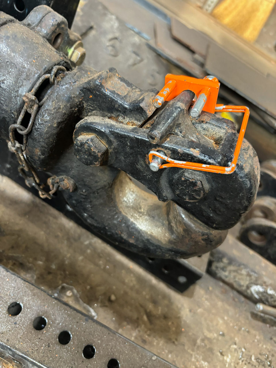 An orange hitch pin with two additional guide pins is fastened securely to a black trailer hitch.