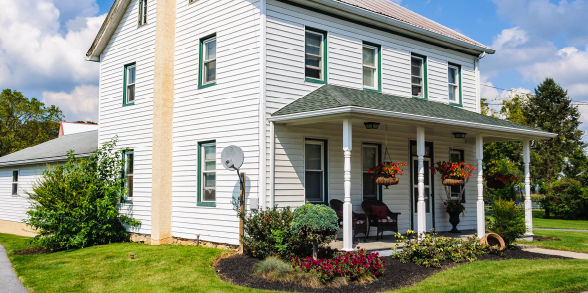 Picture of a white home with green accents and a big, welcoming front porch.