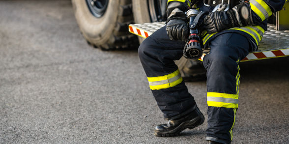 a firefighter sits on a truck while holding a hose