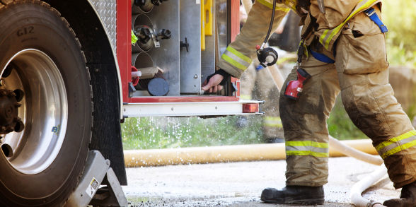 firefighter turning a valve on a firetruck