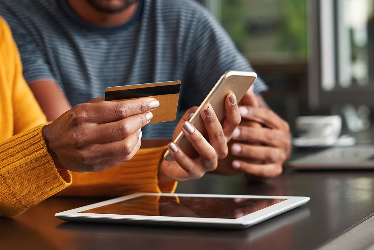 Two people with one holding a phone and a credit card