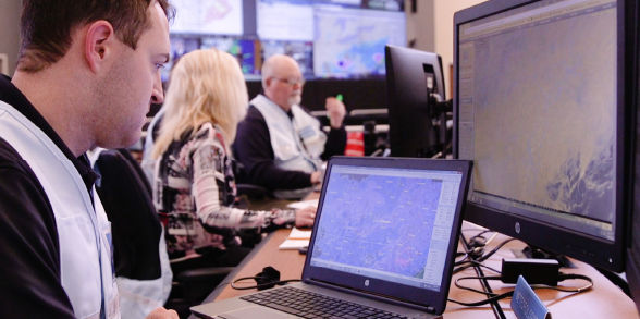 People look at weather models inside the Commonwealtlh Coordination and Response Center.