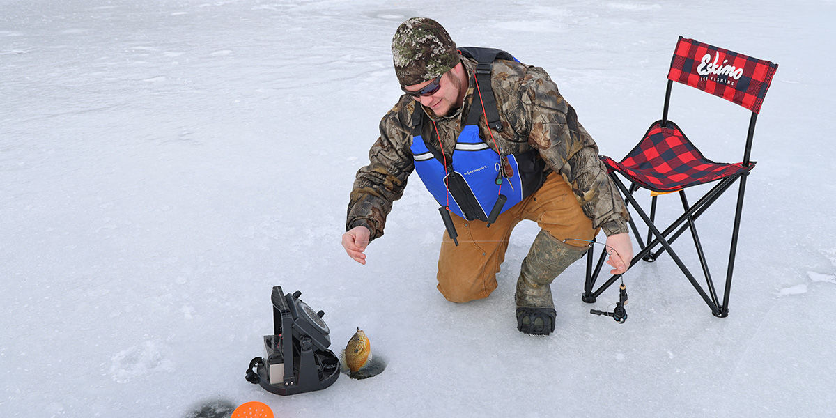 Man wearing layers under a life jacket showcasing his large Bluegill caught while ice fishing on Nessmuk Lake in Tioga County, PA.