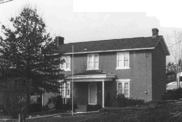 (Two story house with center door and 3 bays across the front façade and a side gabled roof with brick chimneys at the center of each exterior side wall.