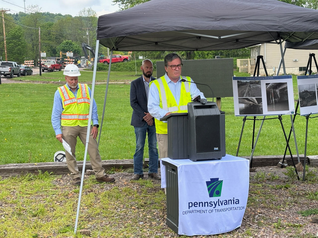 PennDOT Secretary Carroll speaking under a tent at site of U.S. 219 bridge damaged by flood