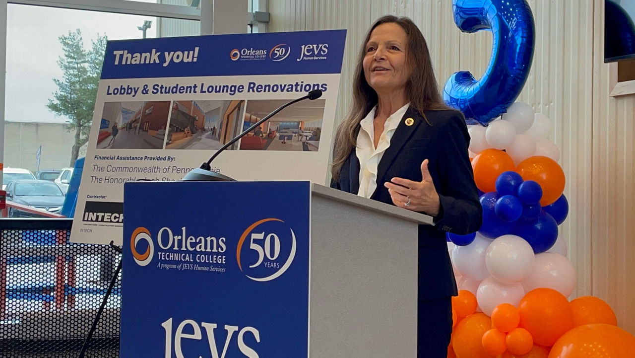 L & I Secretary Nancy A. Walker speaking at a podium with signage and balloons in the background.