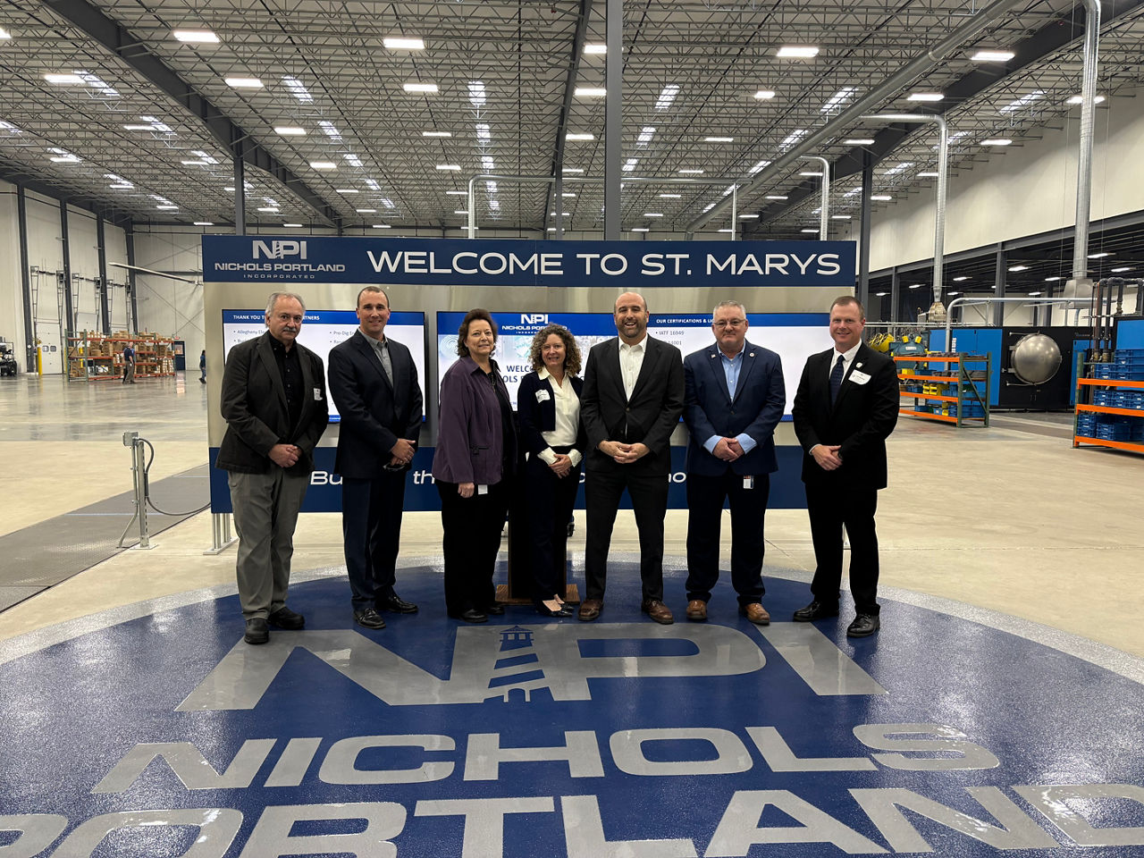 Pennsylvania DCED Secretary Rick Siger and a group of businesspeople pose for a photo in a large modern industrial space.